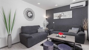 Ein modernes Wohnzimmer mit zwei grauen Sofas, einem Couchtisch und einem dekorativen Spiegel.