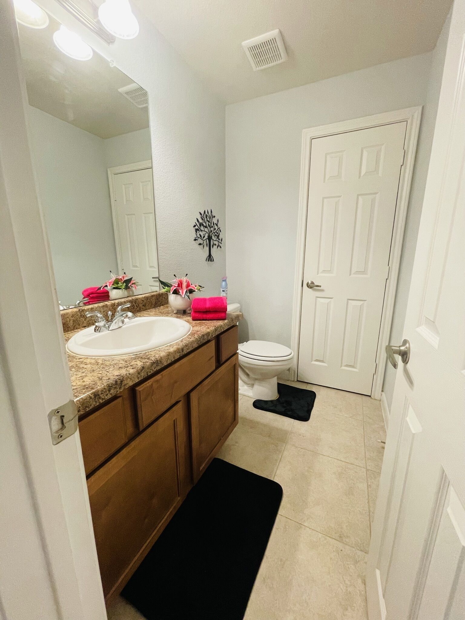 A bathroom with a white sink, wooden vanity, and a white toilet.