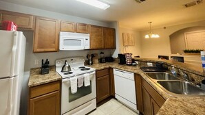 A kitchen with wooden cabinets, a white stove, a microwave, a dishwasher, and a granite countertop.
