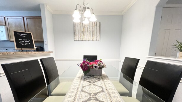 A dining area with a glass table, black chairs, and a floral centerpiece.