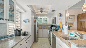 A spacious kitchen with white cabinetry, granite countertops, and a central island with a sink. - Crystal Sands Tower Unit 1007 - Beachfront (Sarasota)