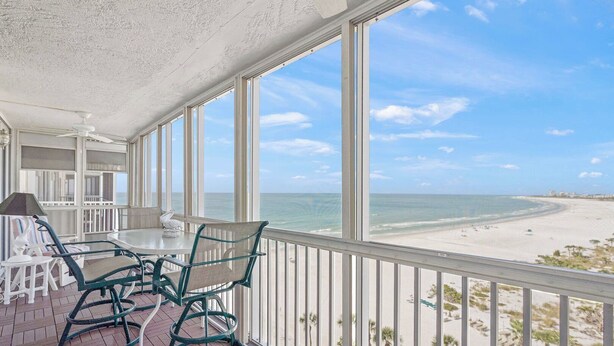A balcony with a table and chairs, overlooking a beach. - Crystal Sands Tower Unit 1007 - Beachfront (Sarasota)