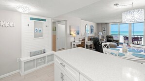 Una cocina moderna con una isla grande, un comedor con vista al océano y una sala de estar decorada con temática playera.