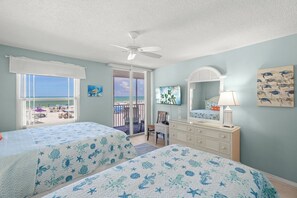 A bedroom with two beds, a dresser, a chair, a ceiling fan, and a view of the beach. - Crystal Sands Tower Unit 204 - Beachfront (Sarasota)