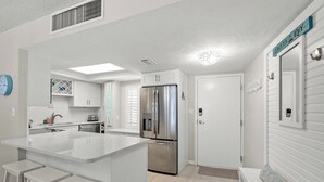 Una cocina moderna con una isla central, electrodomésticos de acero inoxidable y una decoración en tonos blancos.
