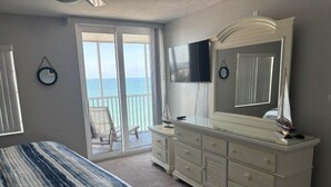 Ein Schlafzimmer mit Bett, Schminktisch, Fernseher und einem Balkon mit Sitzgelegenheit.
