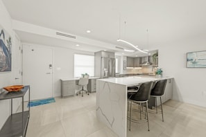 Una cocina moderna con una isla central, taburetes de bar y un comedor.