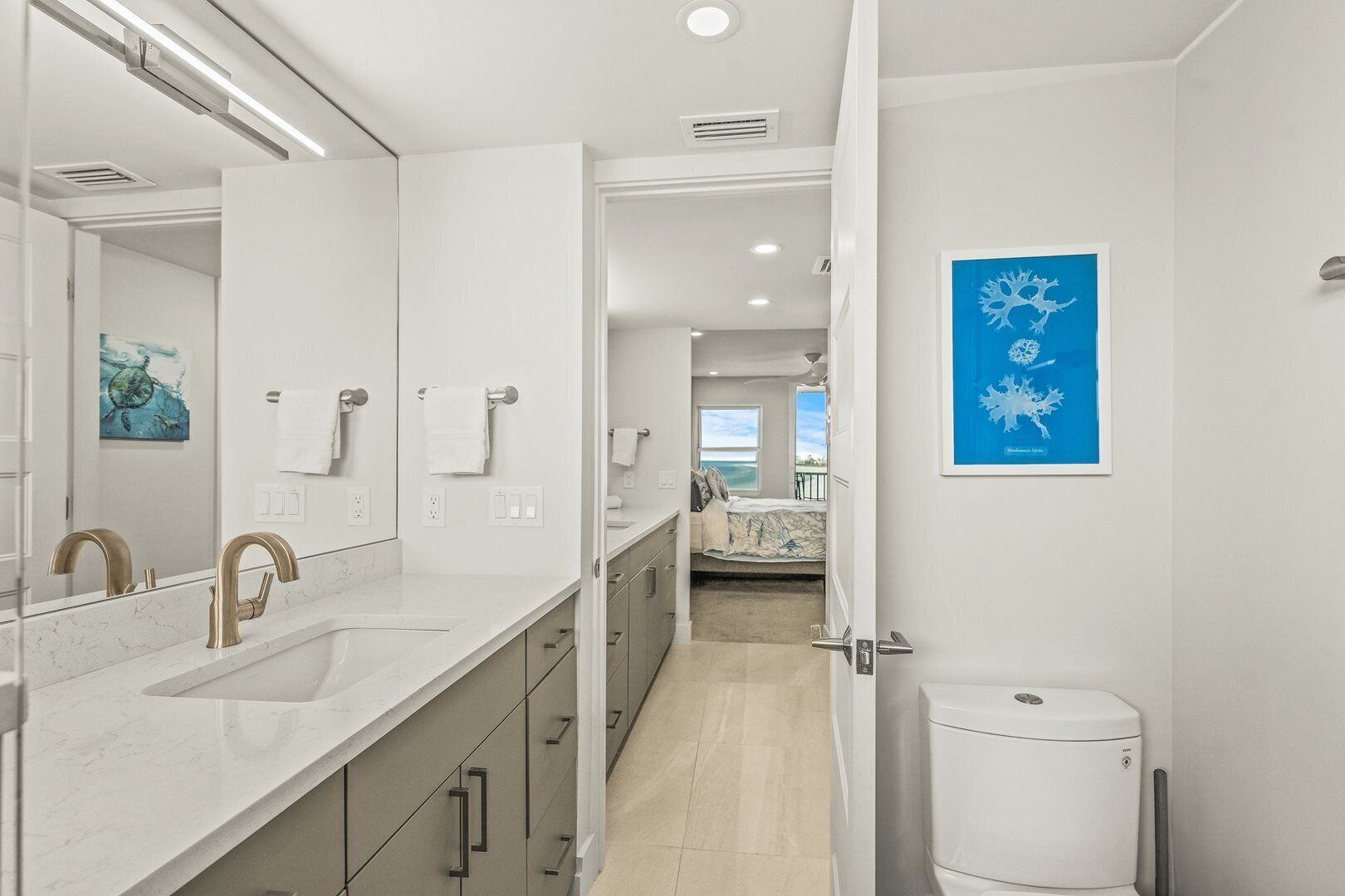 A modern bathroom with a large mirror, dual sinks, and a toilet.