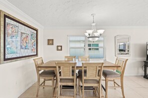 Un comedor con una mesa y sillas de madera, una araña y obras de arte en las paredes.