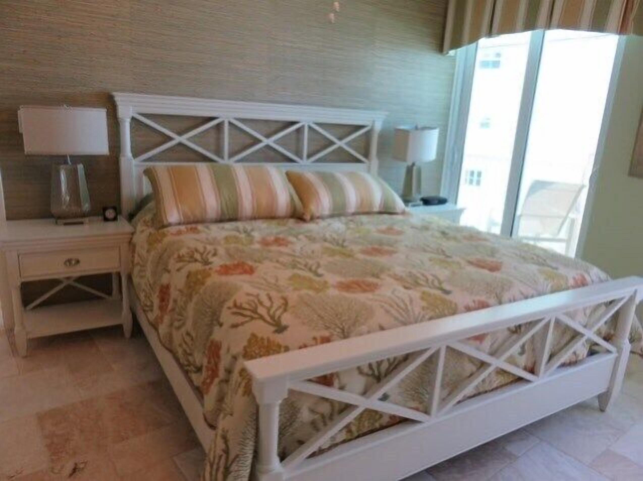 A bedroom with a bed, nightstands, and a window.