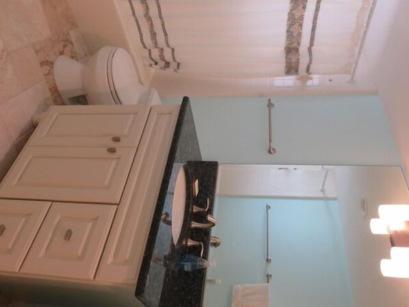 A bathroom with a white vanity, a black countertop, and a glass shower enclosure.
