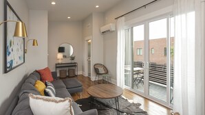 A modern living room with a sofa, a round coffee table, and a view of the outside balcony. - WeHo 3 Story Townhome 3 of 4 w/ Balcony WALKABLE! 8 mins drive to BRDWY!  (Nashville)
