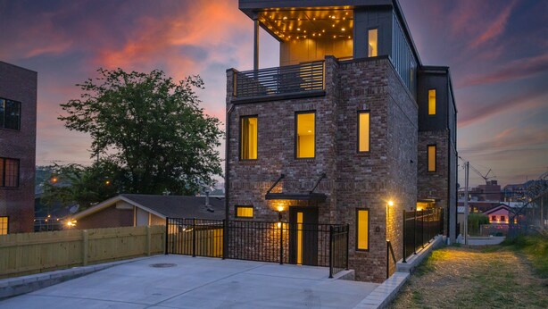 A modern two-story building with a brick facade, multiple windows, and a balcony with string lights. - WeHo 3 Story Townhome 3 of 4 w/ Balcony WALKABLE! 8 mins drive to BRDWY!  (Nashville)