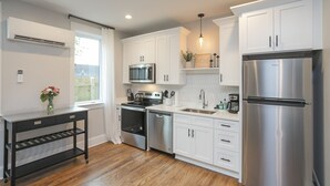A modern kitchen with white cabinets, stainless steel appliances, and a black console table. - WeHo 3 Story Townhome 3 of 4 w/ Balcony WALKABLE! 8 mins drive to BRDWY!  (Nashville)