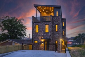 Ein modernes, zweistöckiges Gebäude mit Backsteinfassade, großen Fenstern und einem Balkon mit Lichterketten.