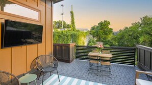 Un patio con televisor, asientos y vista a follaje.