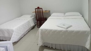 A room with two single beds, a wooden chair, a small table, and a white wall.