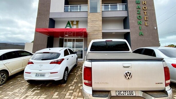 A hotel with a prominent 'AMAZONIA' sign, a red awning, and a Volkswagen pickup truck parked in front.
