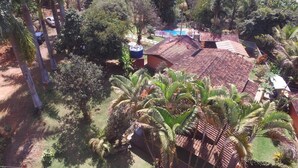 A residential area with a house featuring a tiled roof, surrounded by palm trees and greenery. - Sítio Tôa Tôa - Rio Piracicaba (MG) (Rio Piracicaba)