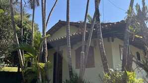 A small, single-story building with a tiled roof, surrounded by tall palm trees and lush greenery. - Sítio Tôa Tôa - Rio Piracicaba (MG) (Rio Piracicaba)