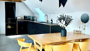 A modern kitchen with a wooden dining table, chairs, and a built-in oven.