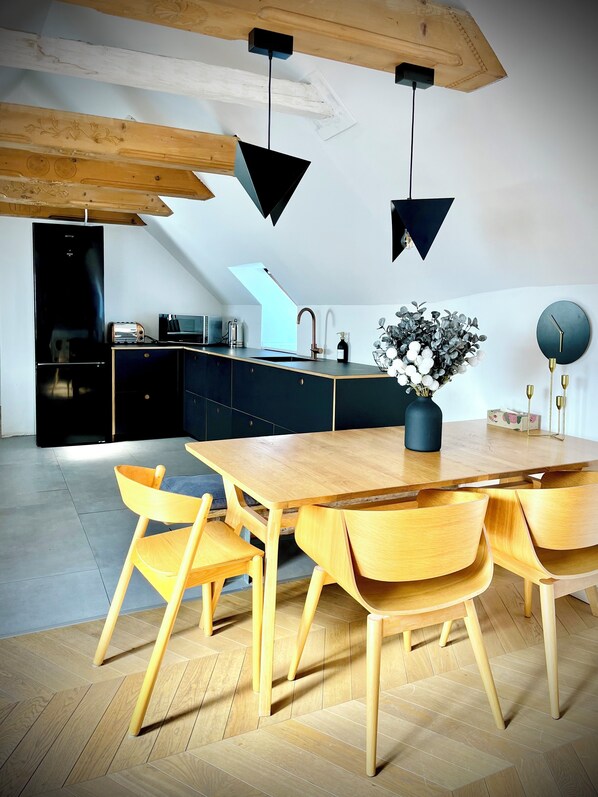A modern kitchen with a wooden dining table, chairs, and a built-in oven. - Steyr Old Town Loft (Steyr)