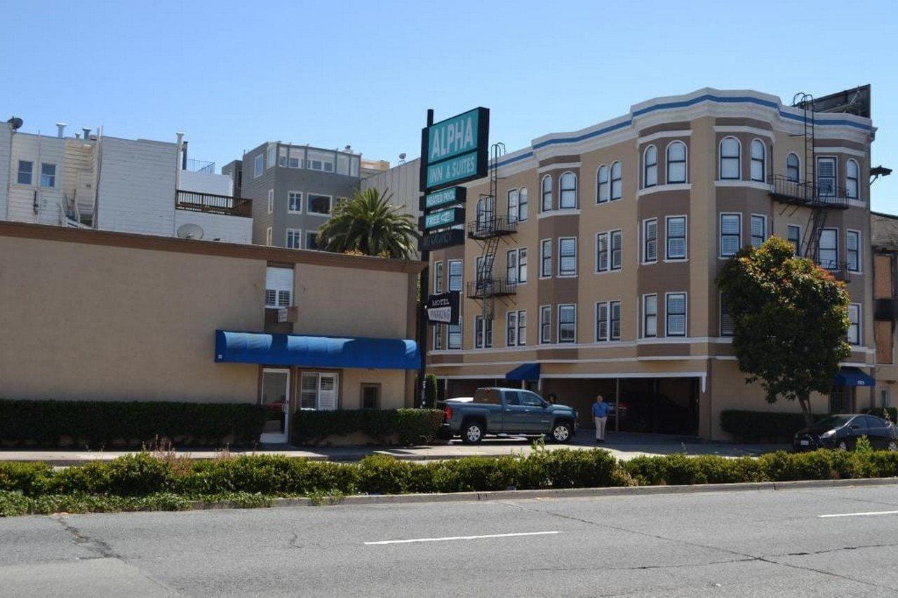 A multi-story building with a sign for 'Alpha Inn & Suites' and a parking sign.