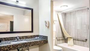 A bathroom with a granite countertop sink, a mirror, a toilet, and a shower with a curtain. - Econo Lodge near Richmond National Battlefield Park (Richmond)