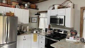 Una cocina con armarios blancos, electrodomésticos de acero inoxidable y un estilo rústico.