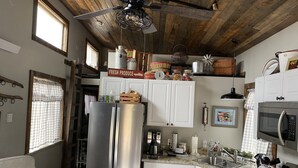 Una cocina con un refrigerador de acero inoxidable, armarios blancos, una estufa y un ventilador de techo.