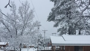 A snow-covered street with a wooden building on the right.