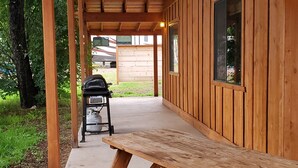 A wooden outdoor patio with a picnic table and a barbecue grill.
