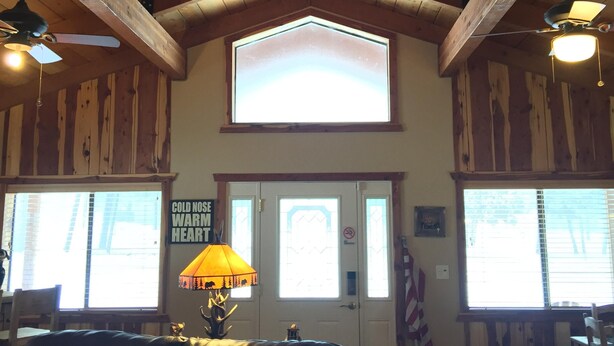 A cozy room with wooden beams, a black leather couch, and a large window with a view.