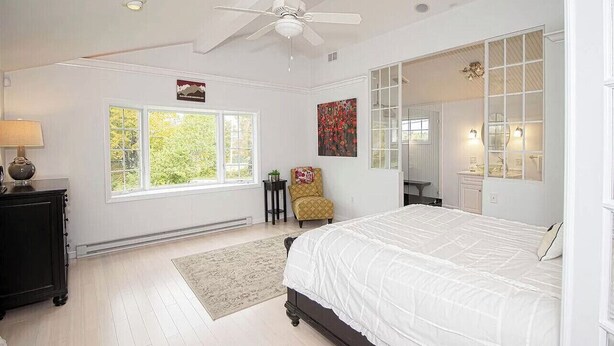A bedroom with a large bed, a ceiling fan, a window, a chair, and a dresser. - Cozy, spacious ski home 10 minutes from Mt. Snow! (Wilmington)