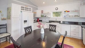 A kitchen with white cabinets, a black dining table, and a clock on the wall. - Cozy, spacious ski home 10 minutes from Mt. Snow! (Wilmington)