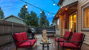 An outdoor patio with two red chairs, a table with dice, and a brick wall.