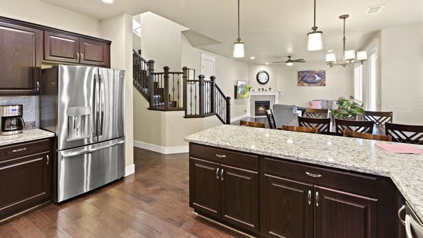 A modern kitchen with dark wood cabinets, stainless steel appliances, and a granite countertop.