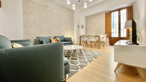 A modern living room with a sofa set, a dining table with chairs, and a desk with a computer. - Opera, Duplex Apartment – Three-bedroom Duplex Apartment (Madrid)