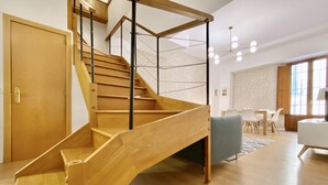 A modern interior with a wooden staircase, a dining area, and a living space. - Opera, Duplex Apartment – Three-bedroom Duplex Apartment (Madrid)