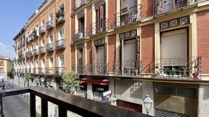 Uma fileira de edifícios com várias andares e sacadas, algumas com plantas.
