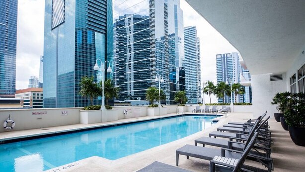 A rooftop pool area with lounge chairs and a view of high-rise buildings. - Luxury Huge APT@Brickell, Free Parking. (Miami)