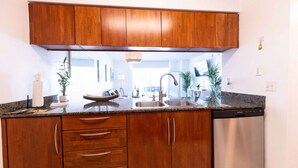A kitchen with wooden cabinets, a stainless steel dishwasher, and a granite countertop. - Luxury Huge APT@Brickell, Free Parking. (Miami)