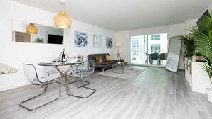 A modern living room with a glass dining table, grey sofa, and large windows. - Luxury Huge APT@Brickell, Free Parking. (Miami)