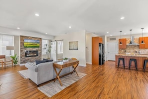 A spacious living room with a fireplace, a grey sofa, and a wooden coffee table.