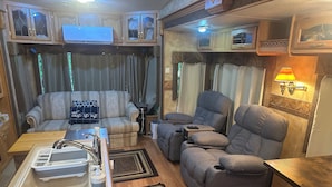 A compact RV interior with a kitchenette, seating area, and a small table. - North Georgia Mountain Getaway (Cleveland)