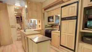 A compact kitchen with wooden cabinets, a stainless steel sink, a built-in stove, and a microwave. - North Georgia Mountain Getaway (Cleveland)