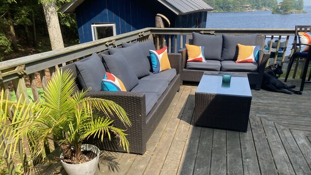A deck with wicker furniture, a potted plant, and a view of a lake. - Clear water and breath taking view! (Trent Lakes)