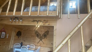 A wooden interior with a staircase, a dining area with white chairs, and a wall-mounted fish decoration. - Clear water and breath taking view! (Trent Lakes)