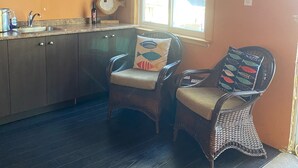 A cozy kitchen with dark wooden cabinets, a round clock, and a window with a view of mountains. - Clear water and breath taking view! (Trent Lakes)