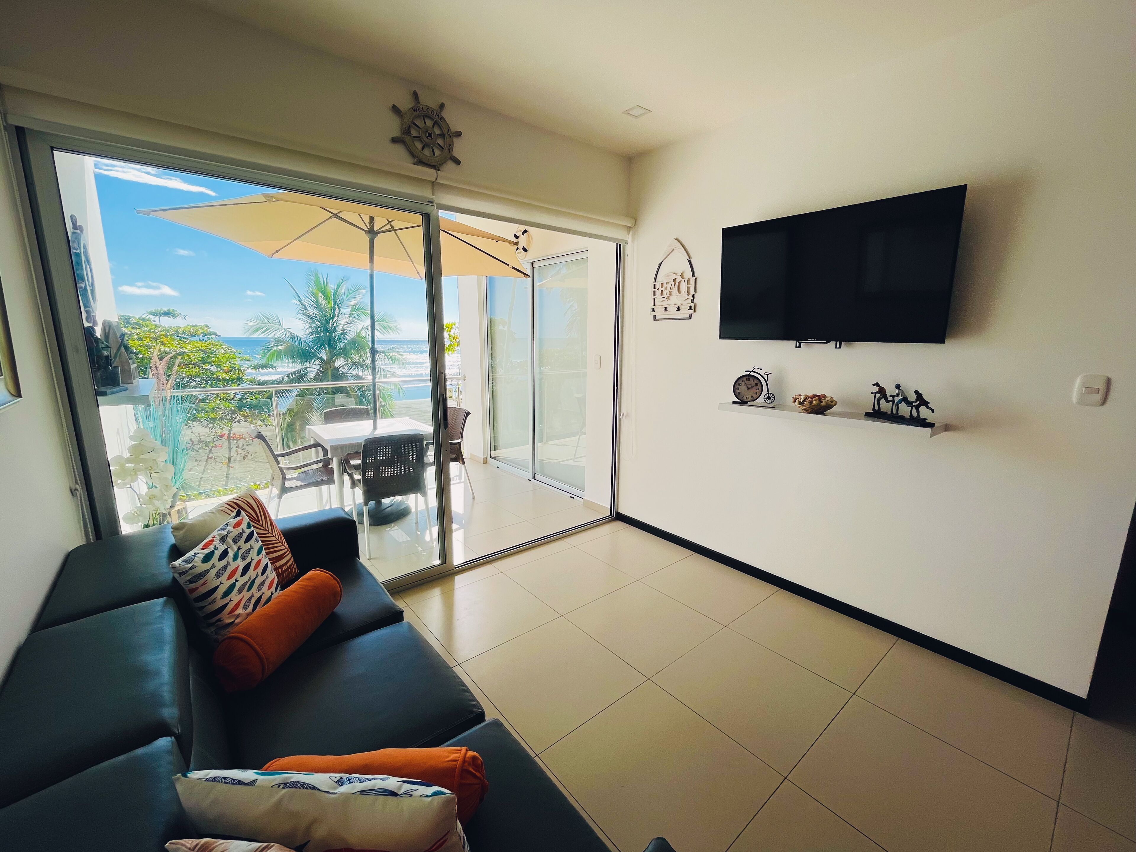 A living room with a sofa, TV, and a view of the outdoors.